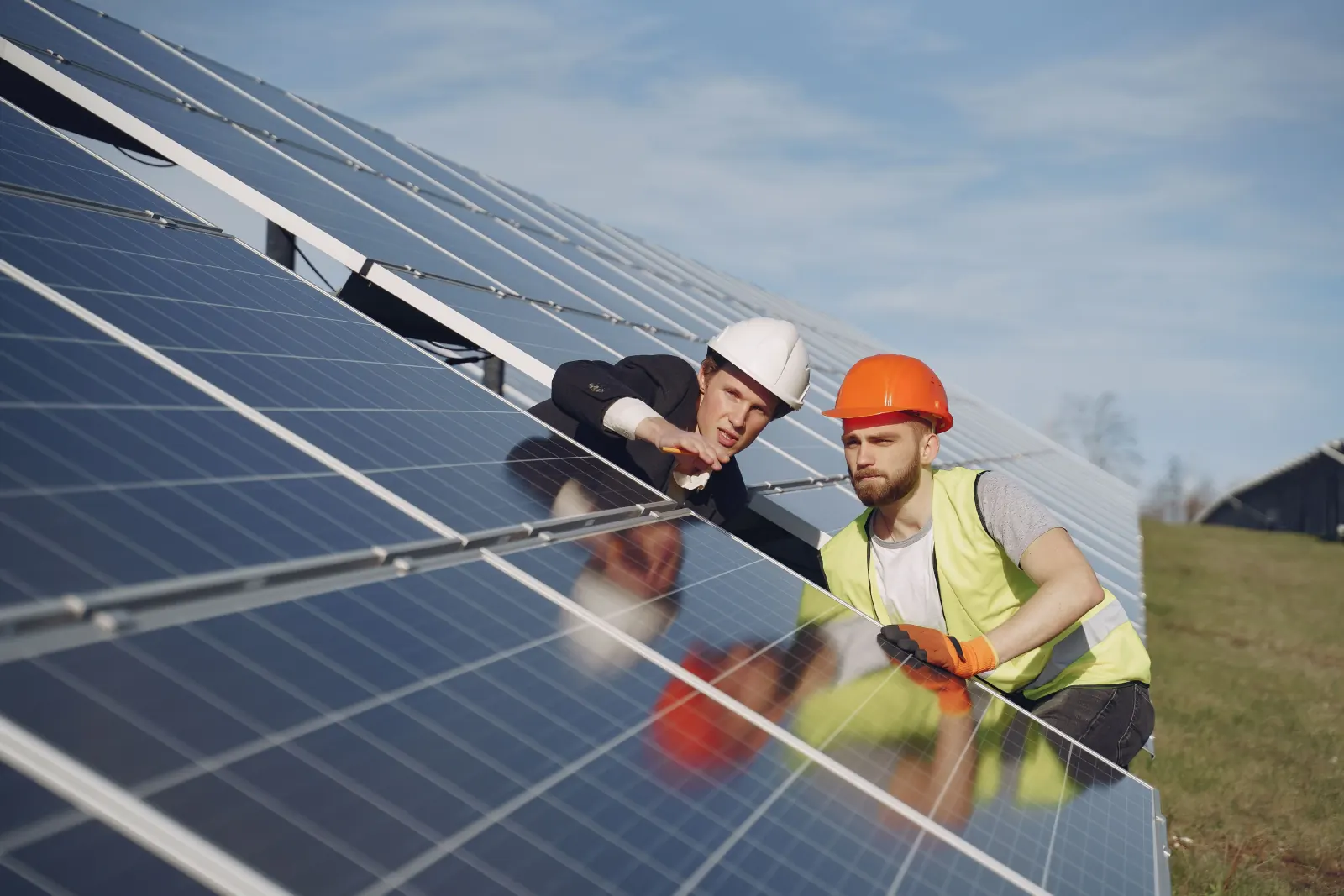 Two people inspecting a row of solar panels on site